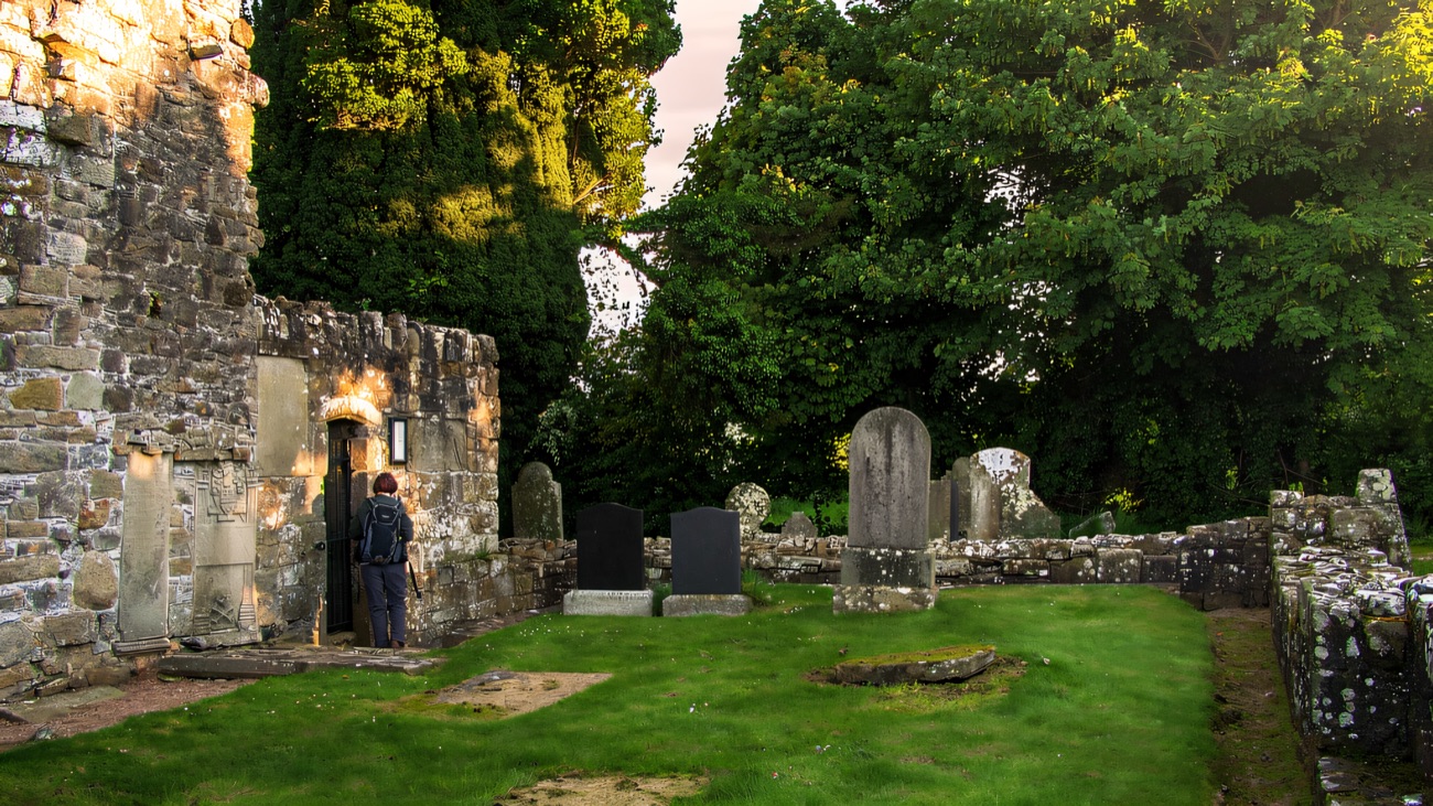The roofless nave and doorway of the old church, set among the graves