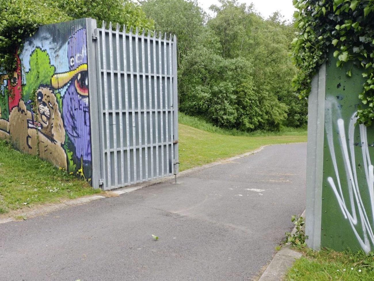 The open gate in the wall at Alexandra Park with painted murals on the panels either side