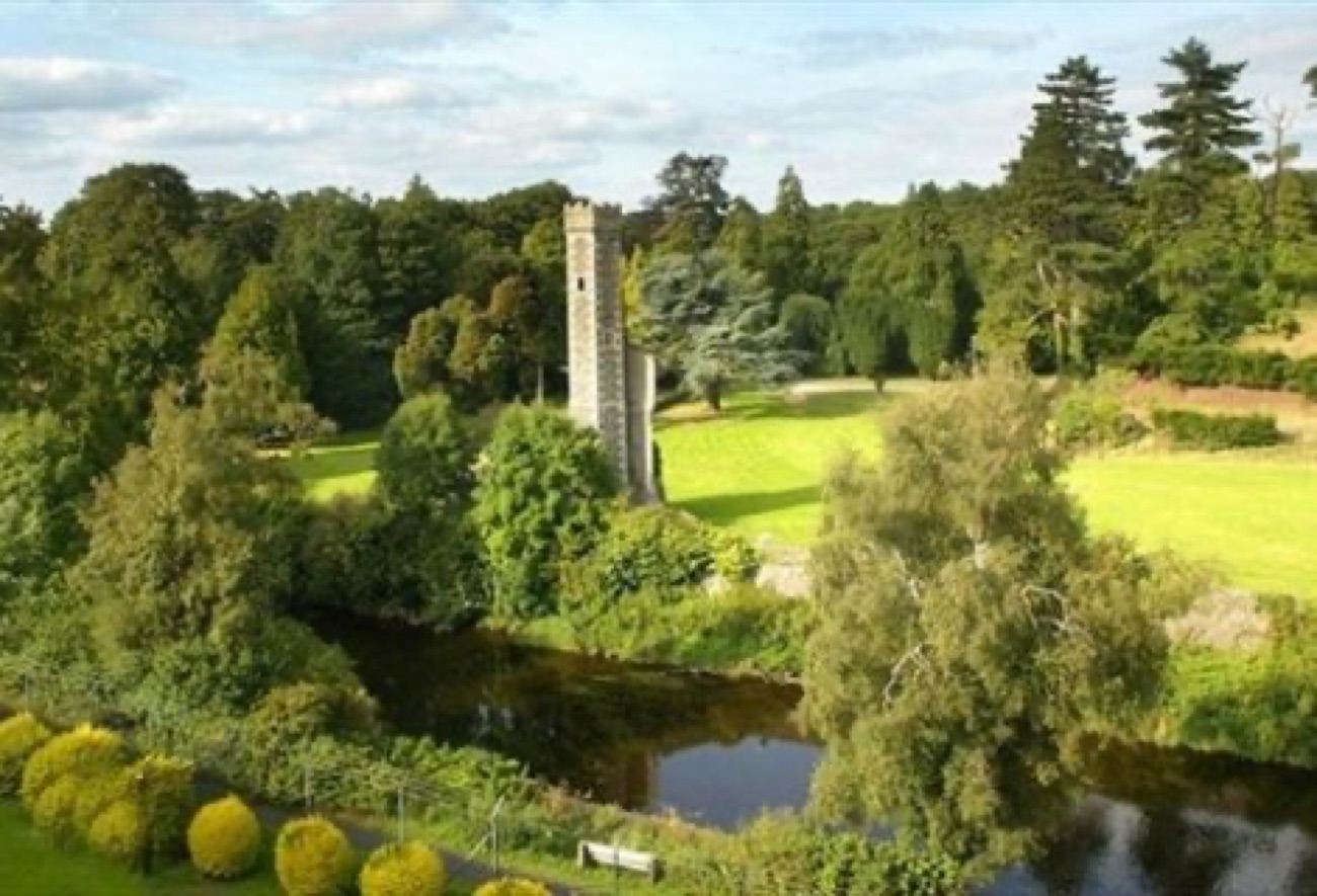 The old round tower on the mound above the river, set among lawns and trees in the grounds