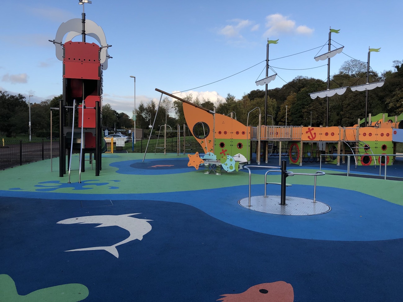 A large pirate-ship themed play park with bright blue and green safety surfacing