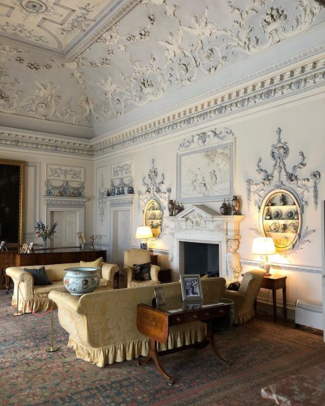 The pale plasterwork drawing room at Ardress House with an ornate decorated ceiling, wall panels and a fireplace