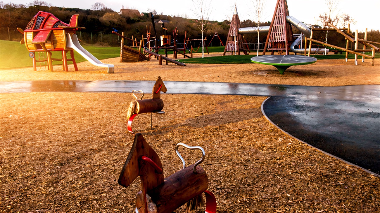 A red aeroplane climber and rocking horses on sand at Ballyarnet Country Park playground