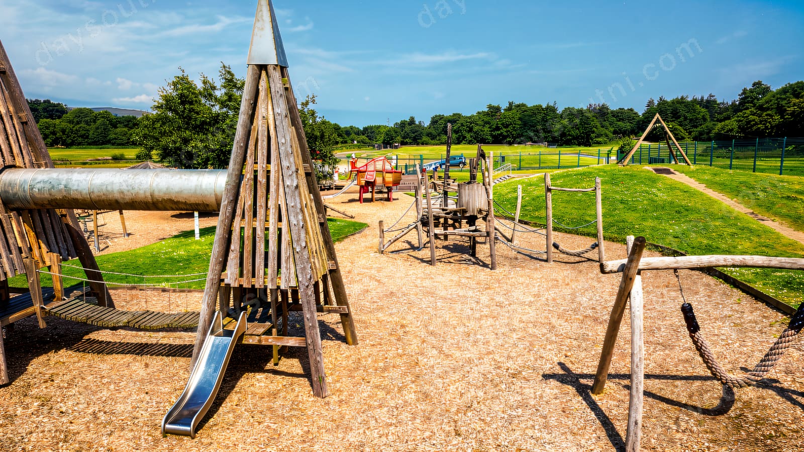 A wide view of the Ballyarnet play park with timber towers and open parkland behind