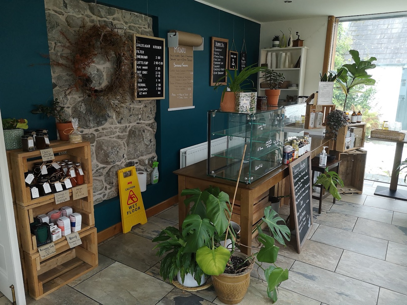 The Ballylagan Kitchen counter, teal wall and bare stone, with the drinks board and shelves of preserves