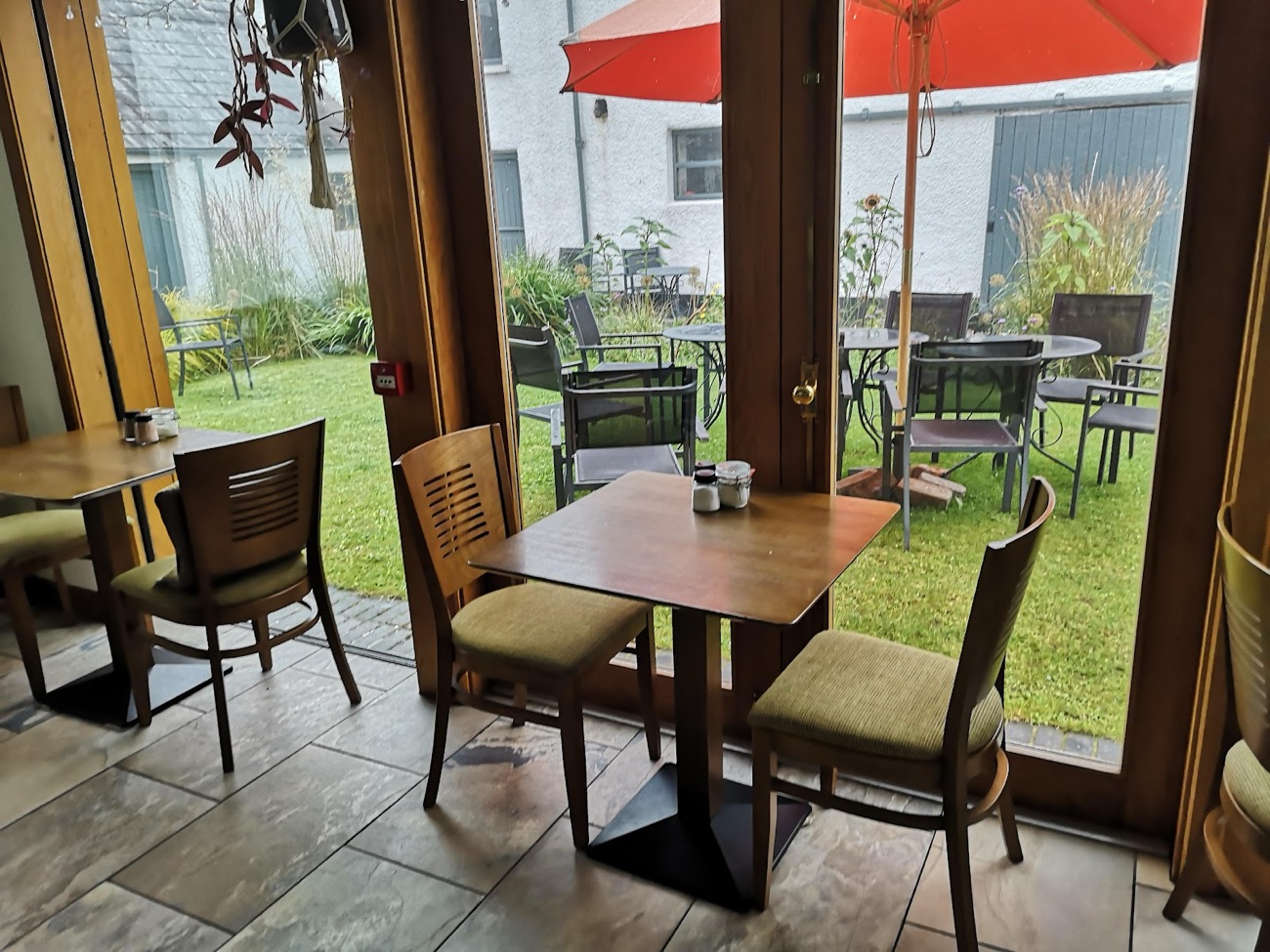 Tables inside the Ballylagan tea room looking out through glass doors to the garden and parasols