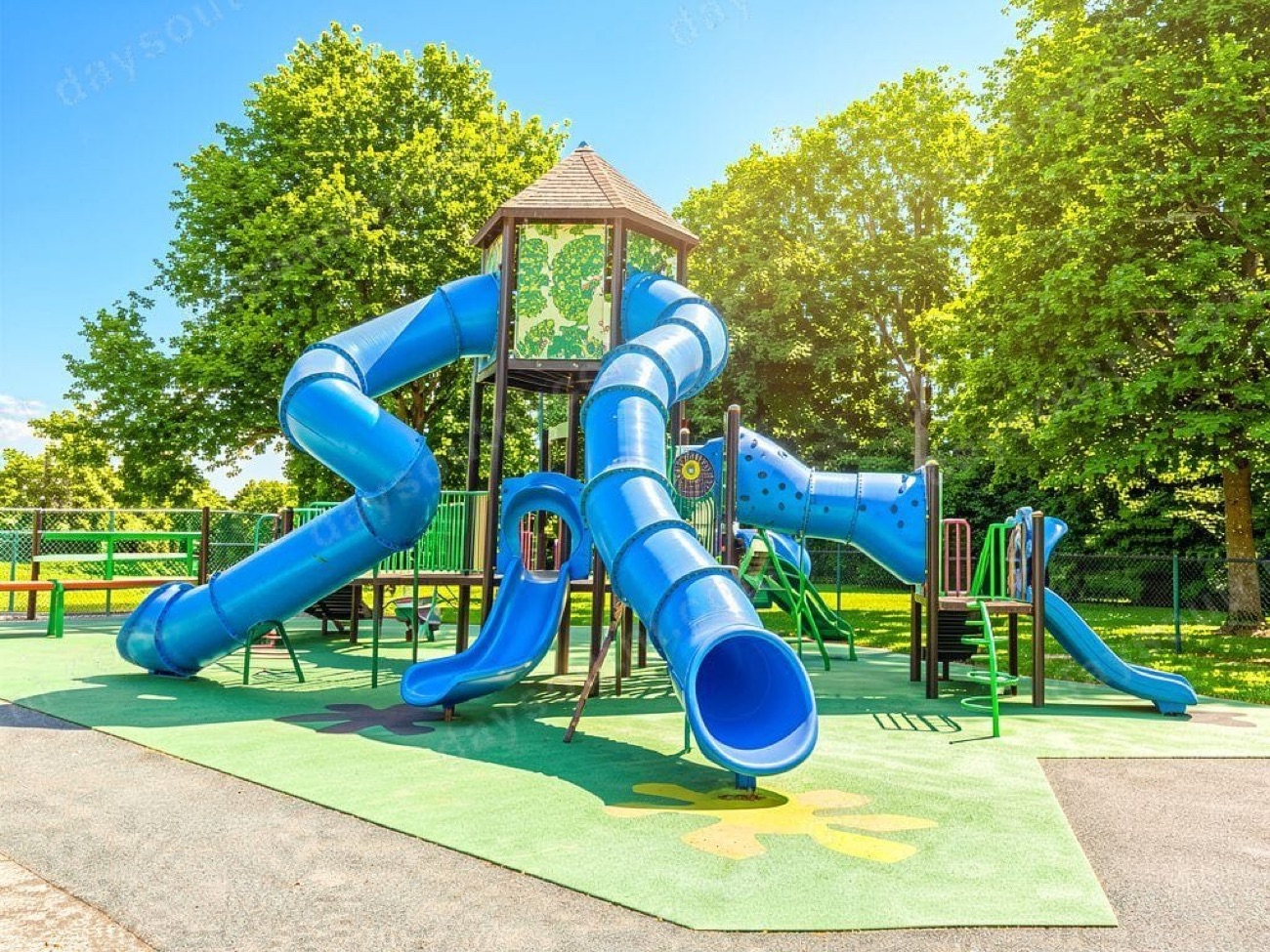 Blue tube slides and a timber-roofed tower on green surfacing at the People's Park play park, Ballymena.