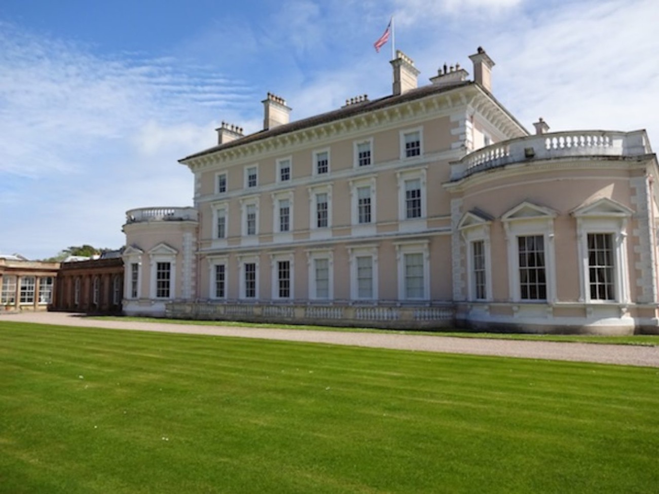 The side elevation of Ballywalter Park mansion across a wide sweep of parkland lawn under blue sky