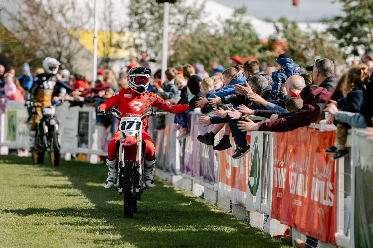 A Bolddog freestyle motocross rider high-fiving children along the barrier of the Balmoral Show main arena