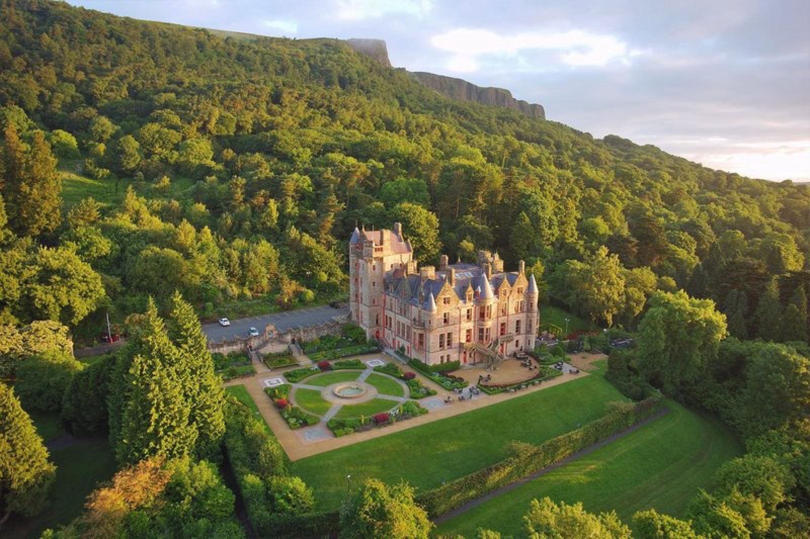 Belfast Castle in golden light with its terraced gardens and the cliff of Cave Hill rising behind