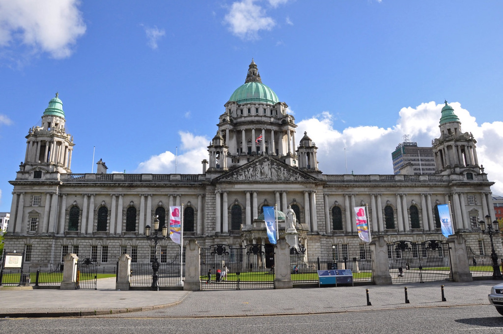 The grand front facade of Belfast City Hall in Portland stone with its green copper domes against a blue sky