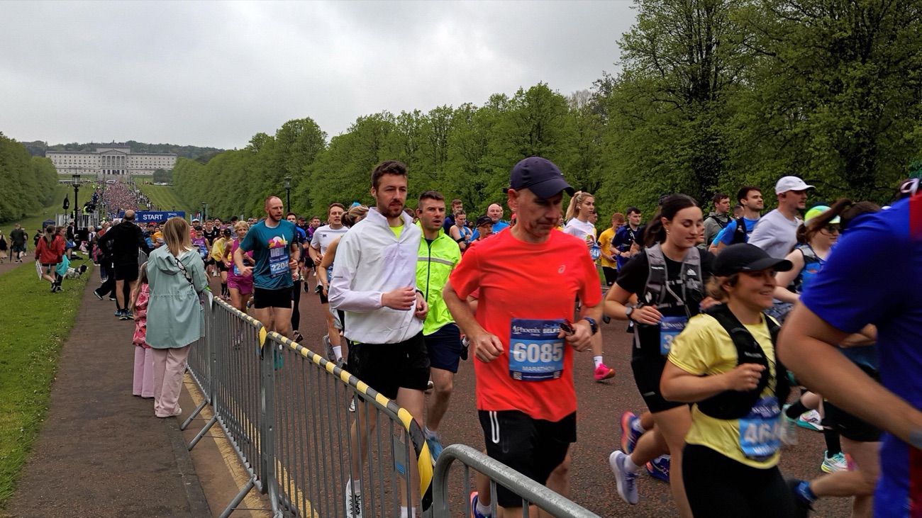 Runners on the tree-lined avenue at Stormont with the Parliament Buildings in the distance at the Belfast City Marathon start