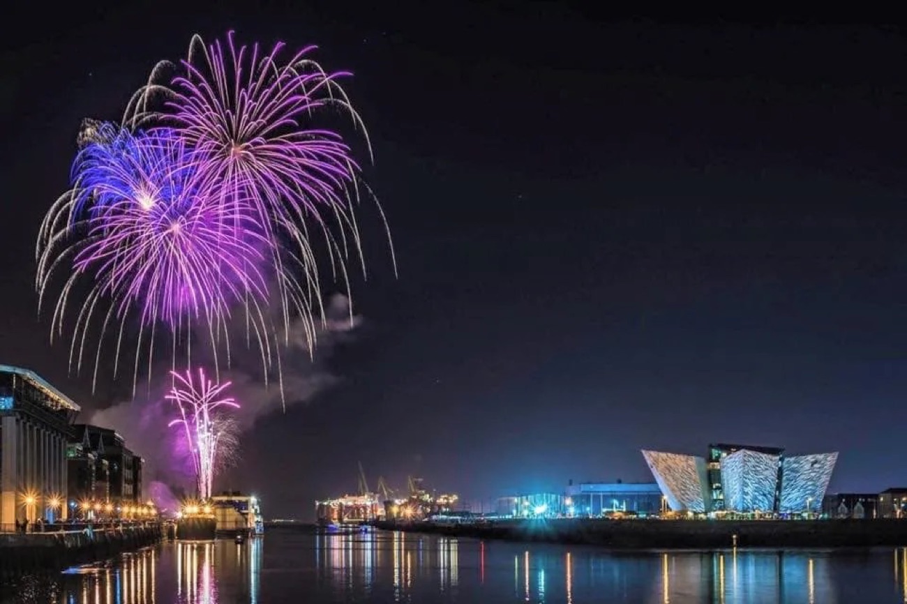 Purple fireworks over the River Lagan reflected in the water beside Titanic Belfast