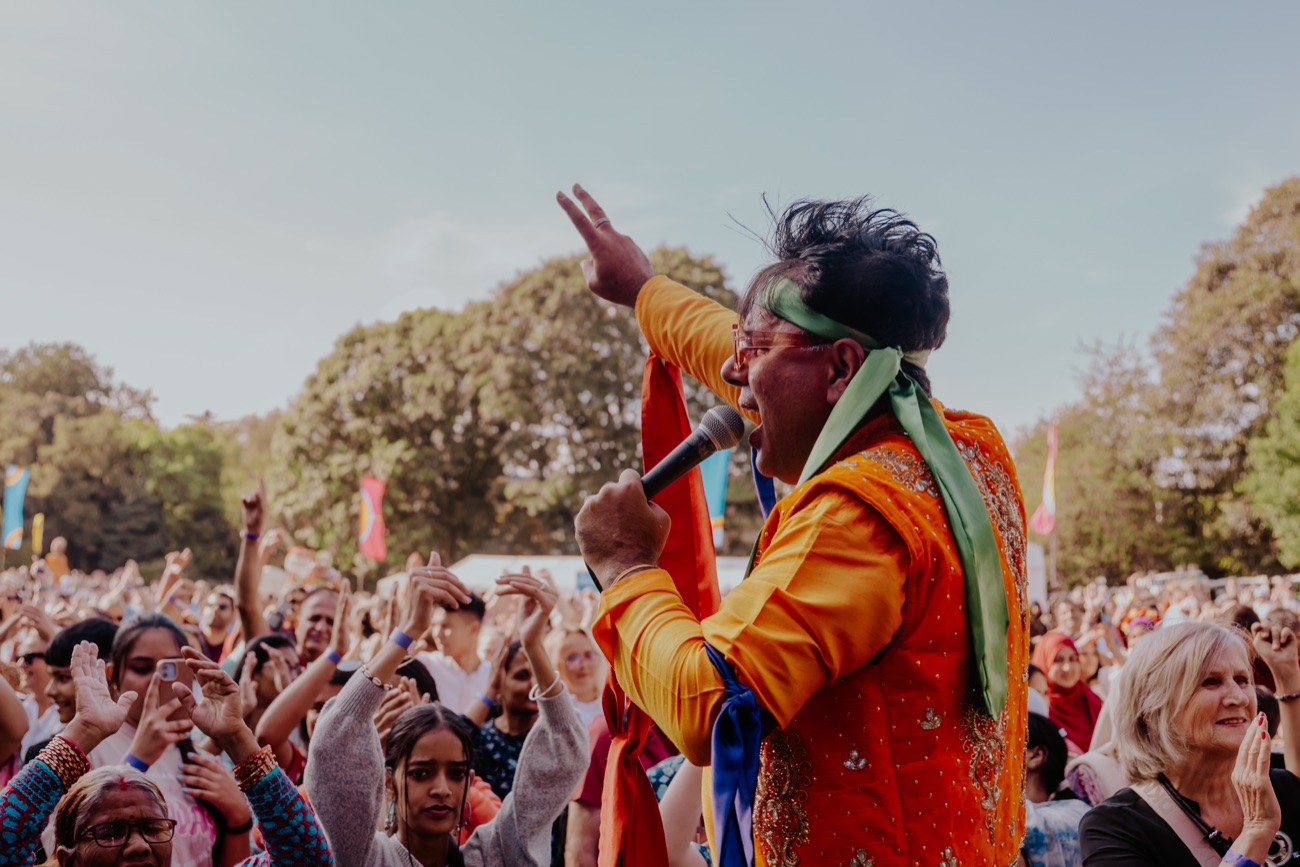 A performer leading a huge crowd on the main stage at Mela Day in Botanic Gardens