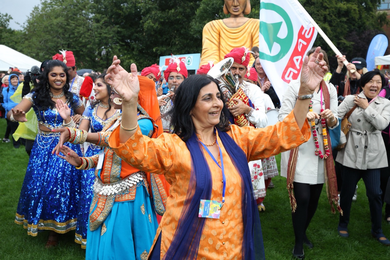 Dancers in vivid South Asian dress celebrating among the crowd at Belfast Mela in Botanic Gardens