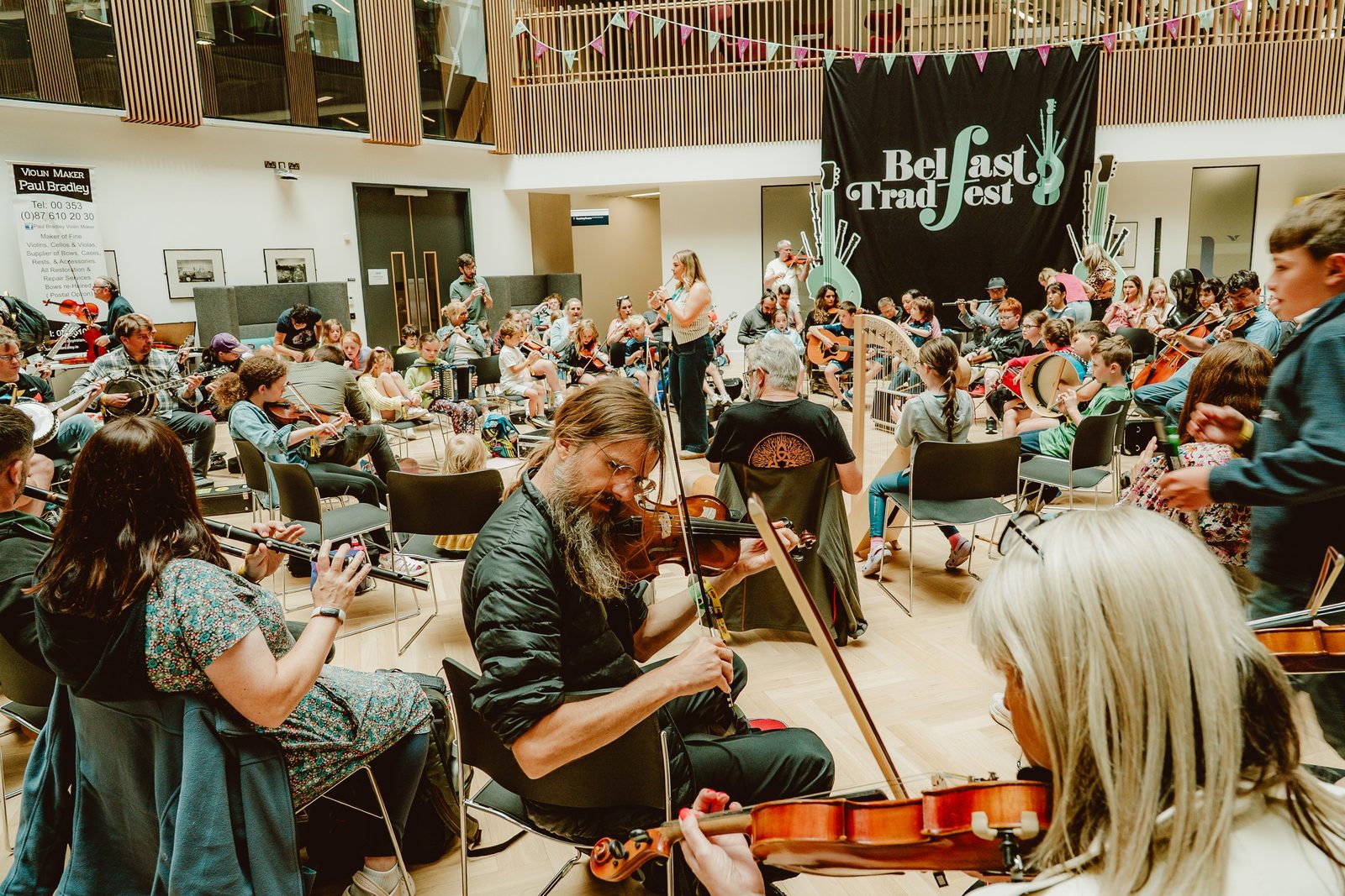 Traditional Irish musicians playing fiddle and flute in a lively pub session at Belfast TradFest