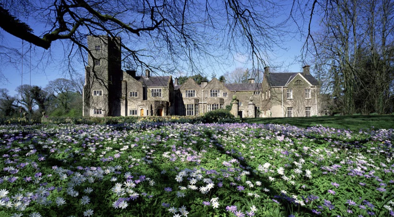 Belle Isle Castle behind a spring carpet of purple flowers under bare trees