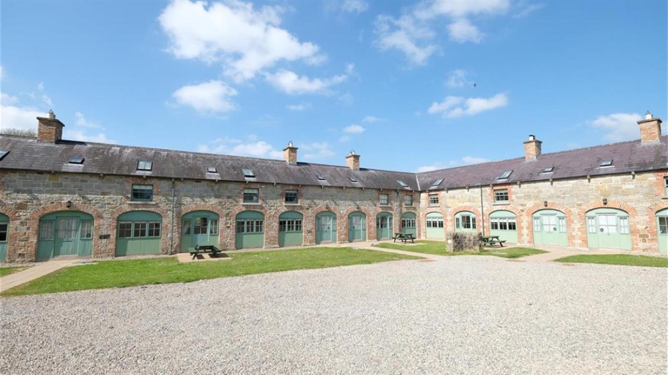 The estate courtyard of stone cottages with green-painted arched doors and picnic tables