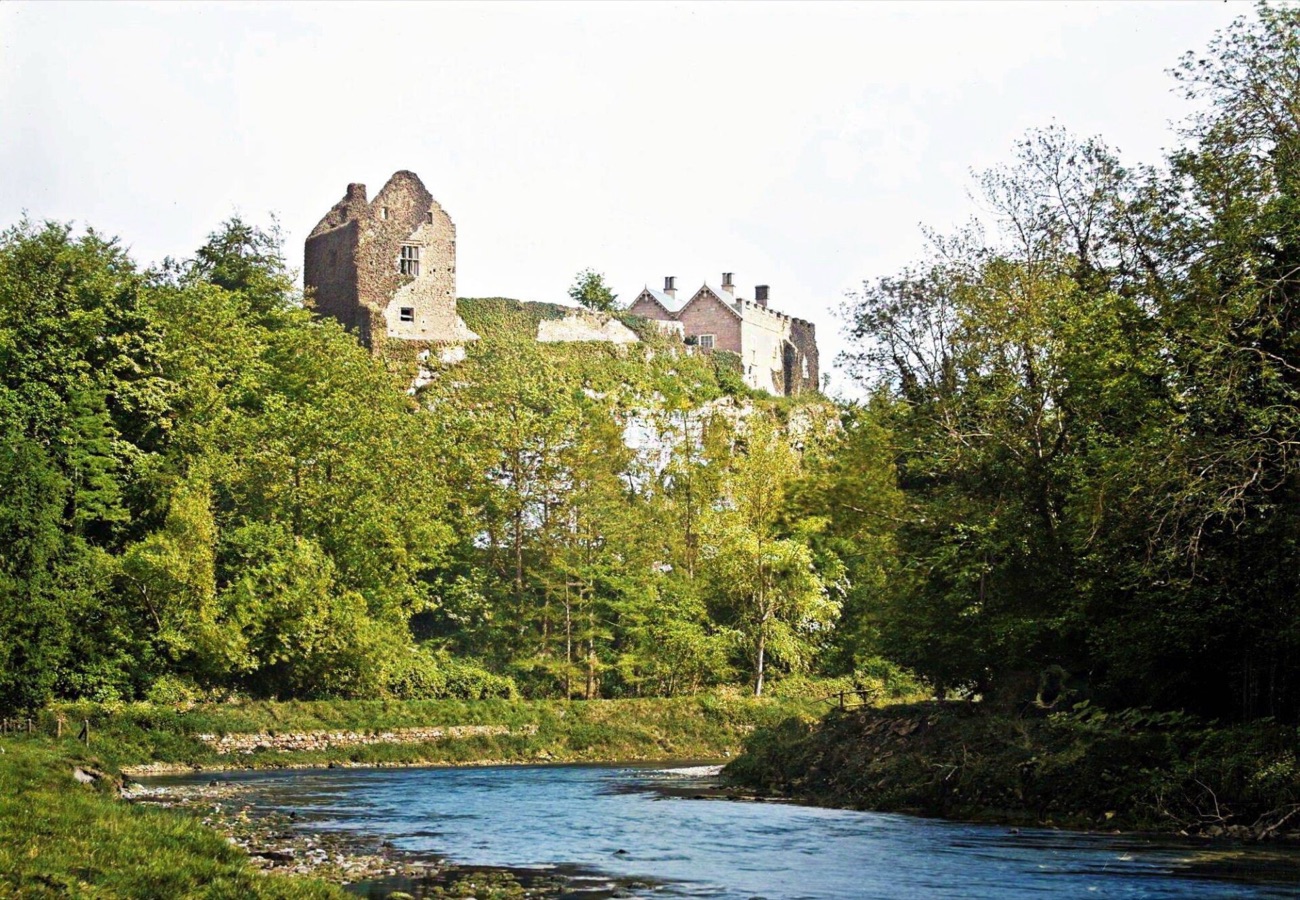 Benburb Castle perched high on the cliff, its towers rising out of the trees above the River Blackwater running below