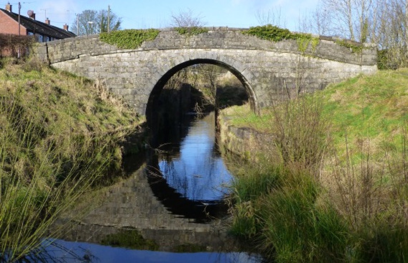 A stone hump-back bridge over the restored Ulster Canal at Benburb, its arch reflected in the still water