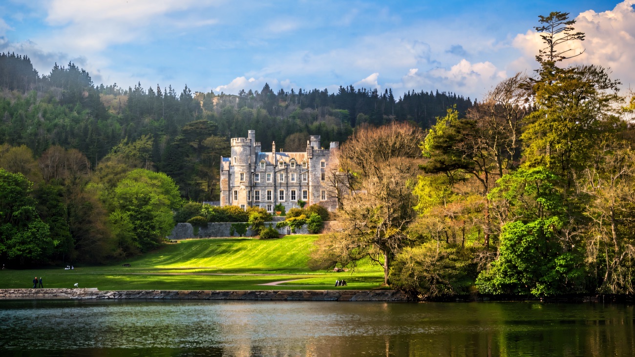 Castlewellan Castle above green lawns and the lake on a bright day