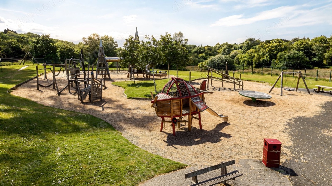 Timber climbing structures and an aeroplane climber on sand at Ballyarnet Country Park playground, Derry