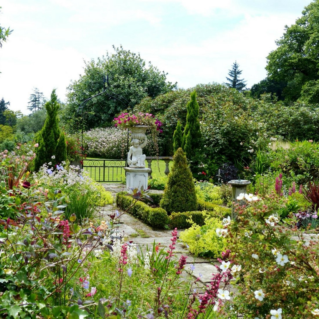 The estate's formal garden with a stone statue and flower borders in bloom