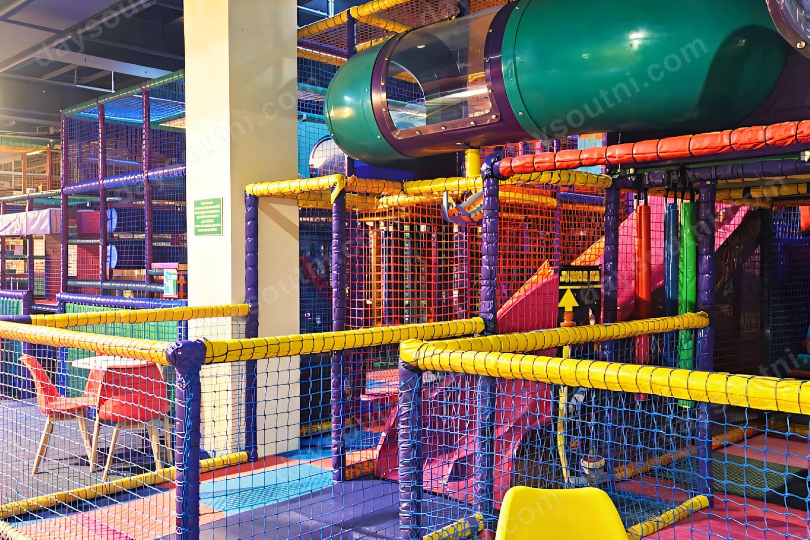 The colourful city-of-play themed soft play frame at Bonkers in the Richmond Centre, Derry, with a green tube slide and netting