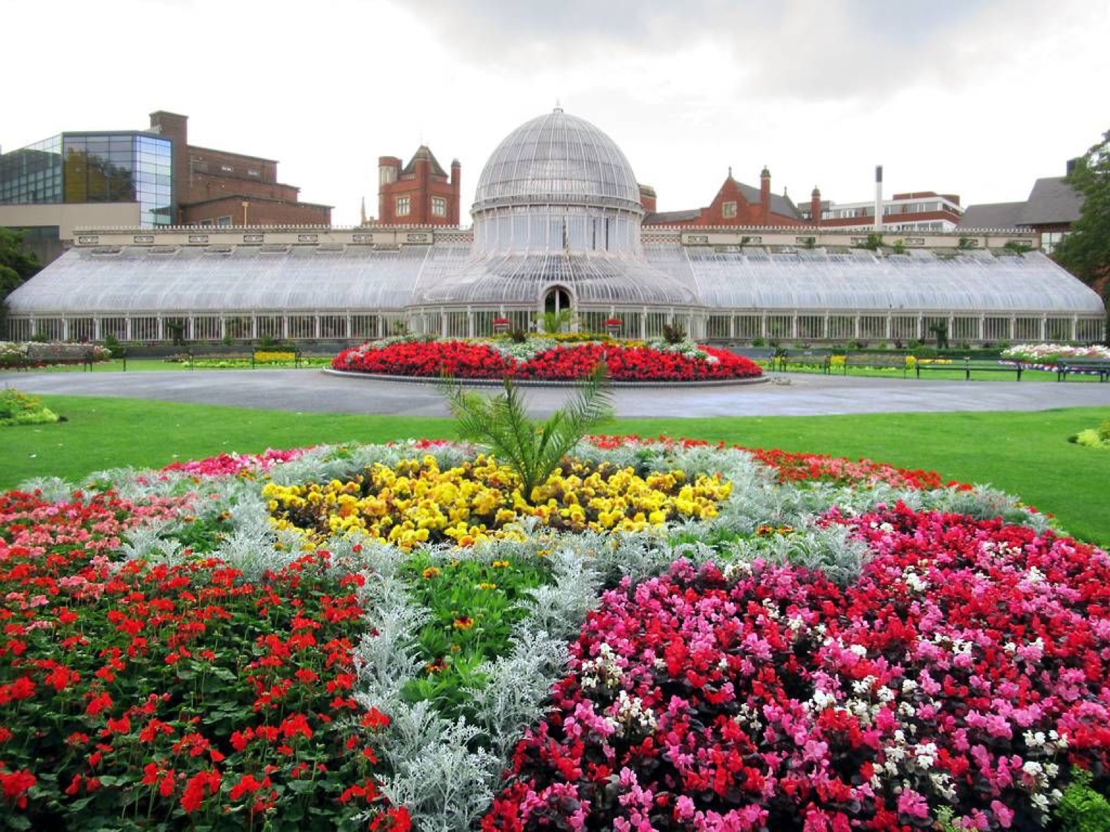 The cast-iron and glass Palm House with its domed centre behind formal flowerbeds and green lawn