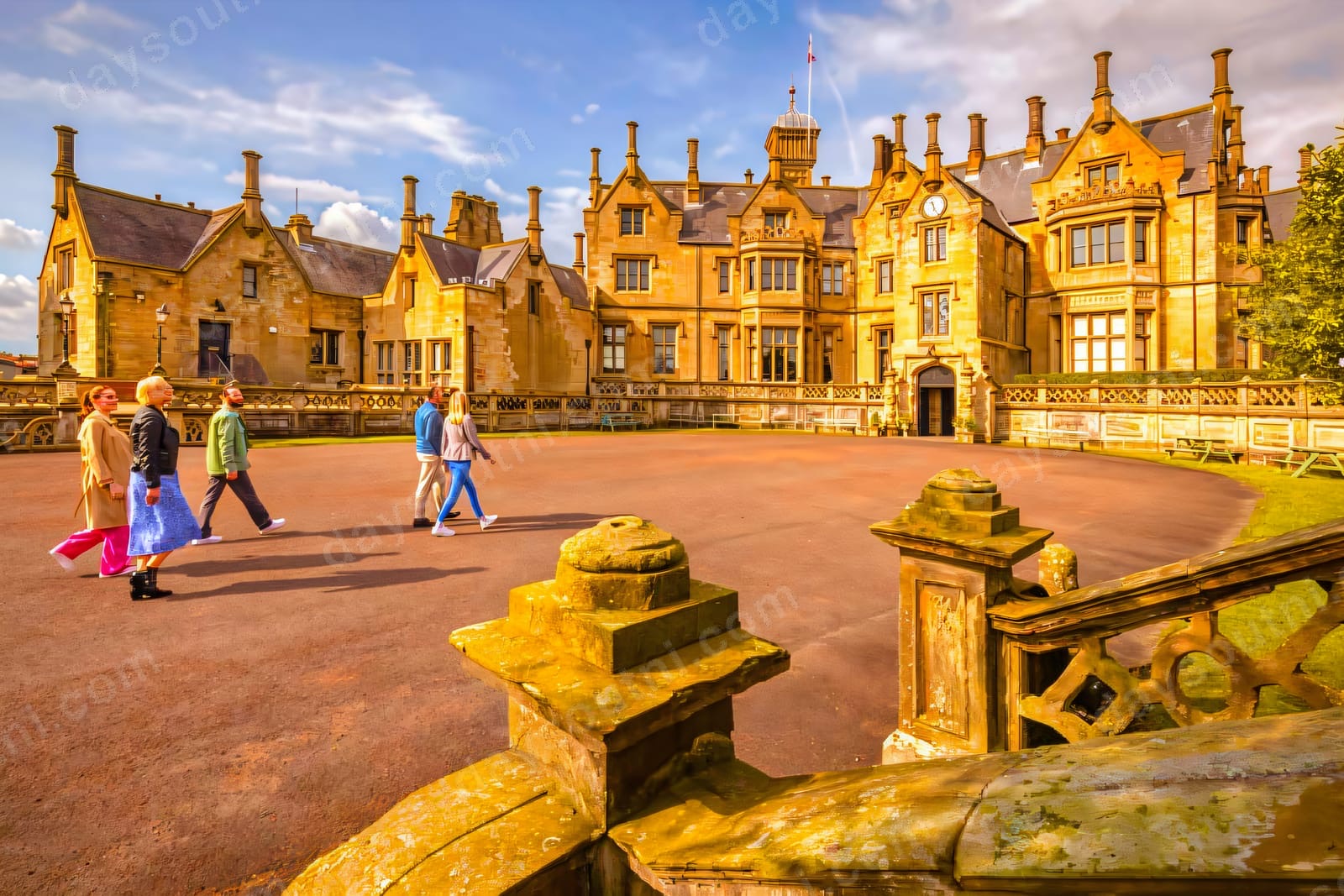 The pale sandstone front of Brownlow House with its turrets, gables and tall chimneys under a bright sky