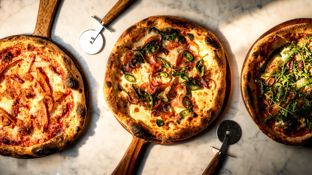 Freshly made pizzas laid out on a wooden table