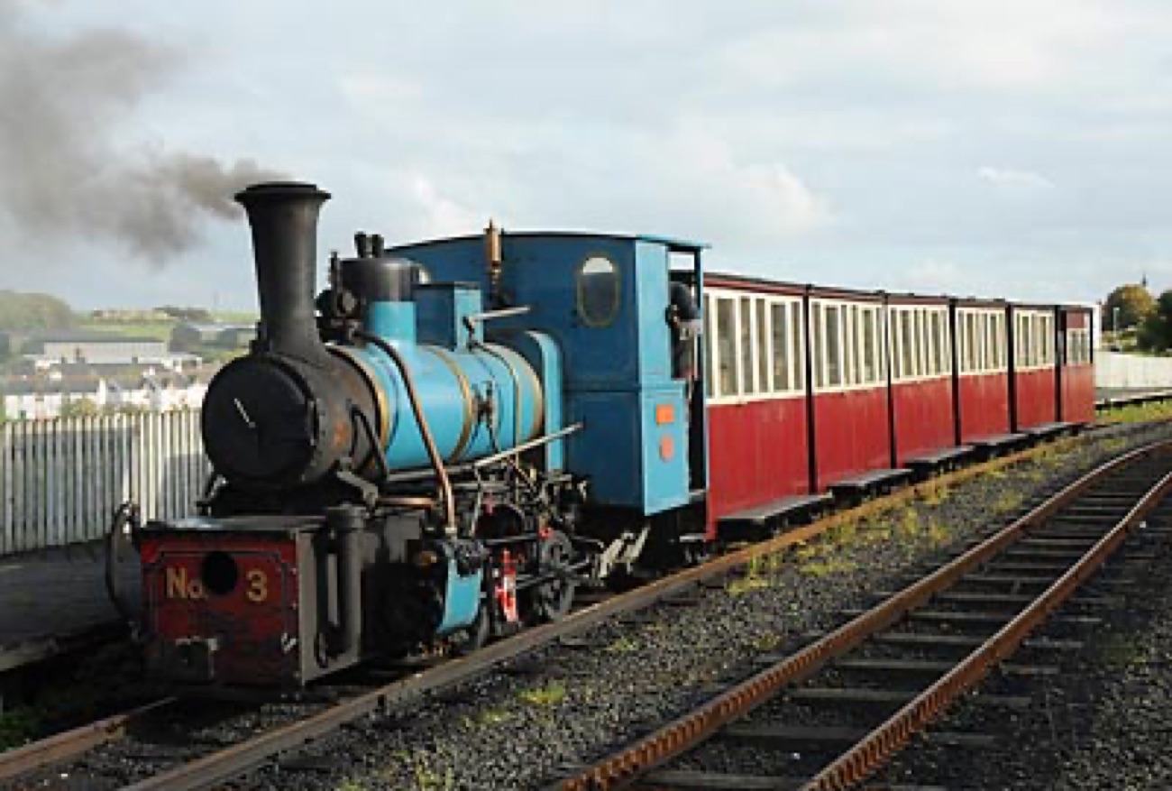 A blue steam locomotive numbered 3 pulling red-and-cream vintage carriages