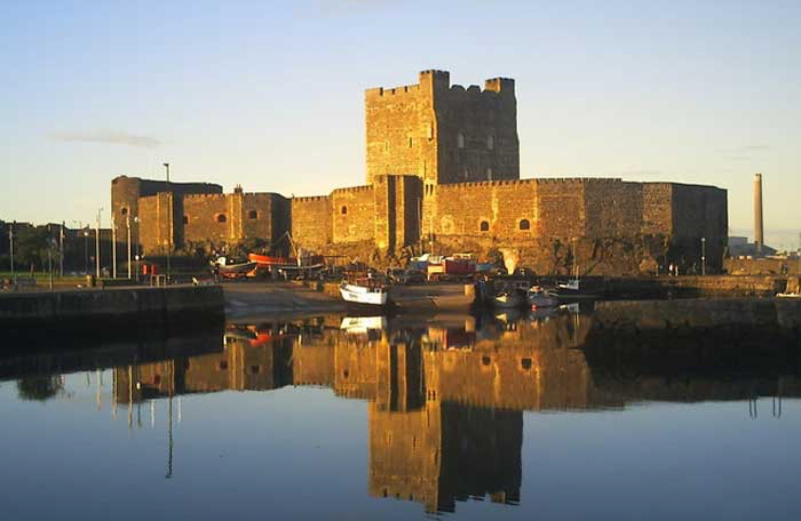 Carrickfergus Castle mirrored in the still harbour water at golden hour