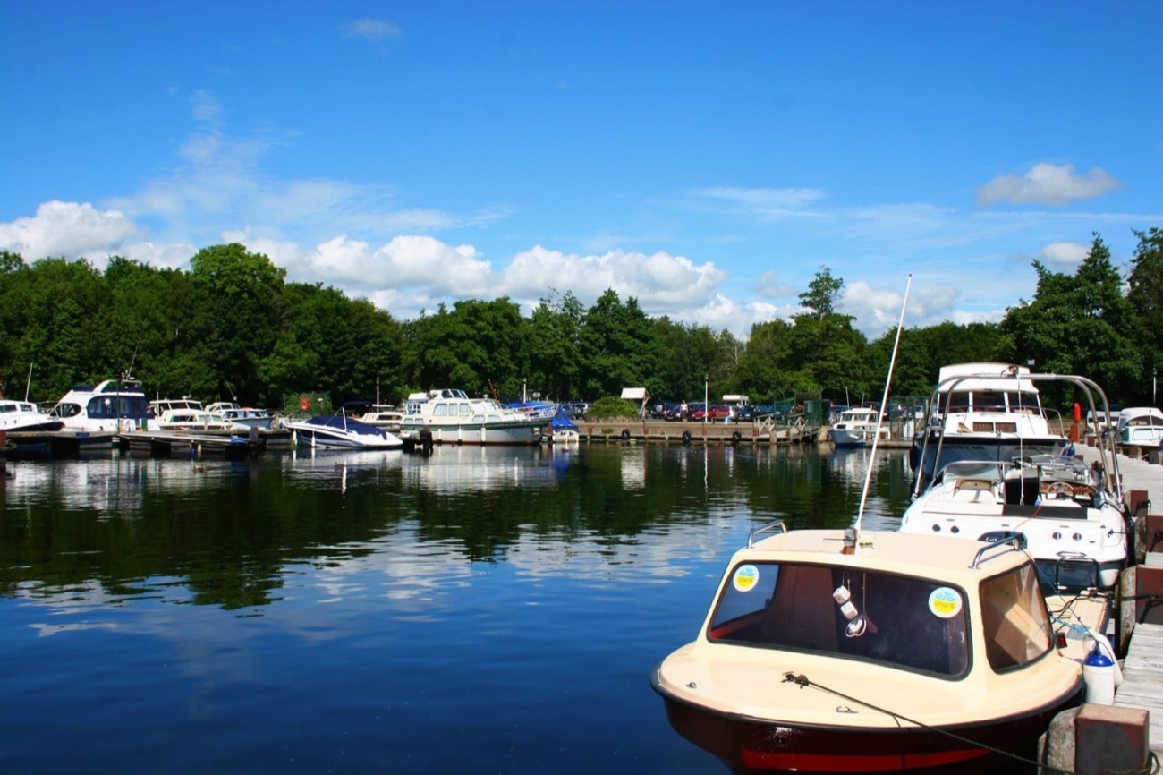 Castle Archdale marina on Lower Lough Erne, small cruisers and motorboats moored along the pontoons with wooded shore behind