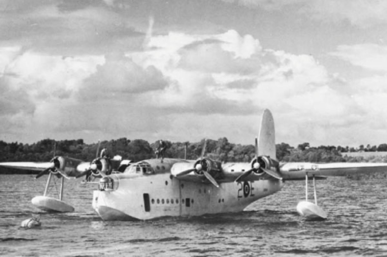 A historic black-and-white photograph of a wartime Short Sunderland flying boat sitting on the water
