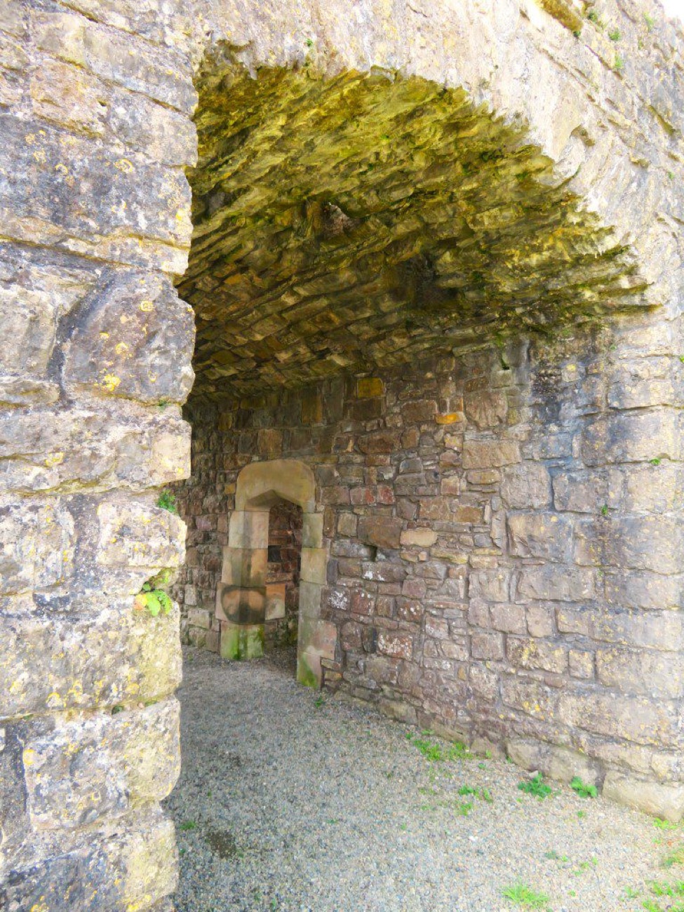The stone gatehouse arch at Castle Caulfield, a moss-covered vaulted passage leading through to an inner doorway