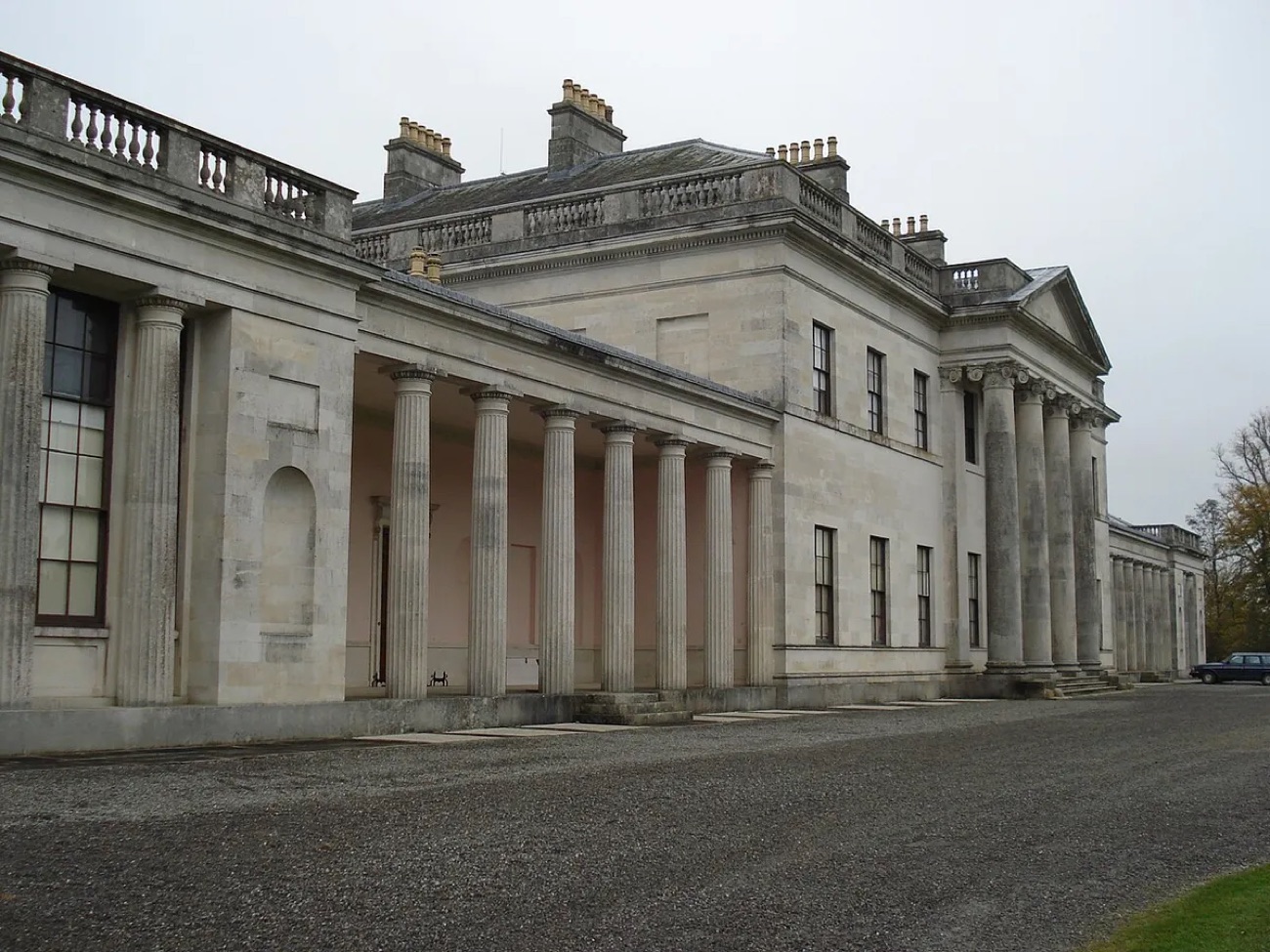 An angled view of the colonnaded portico and pale stone flank of Castle Coole