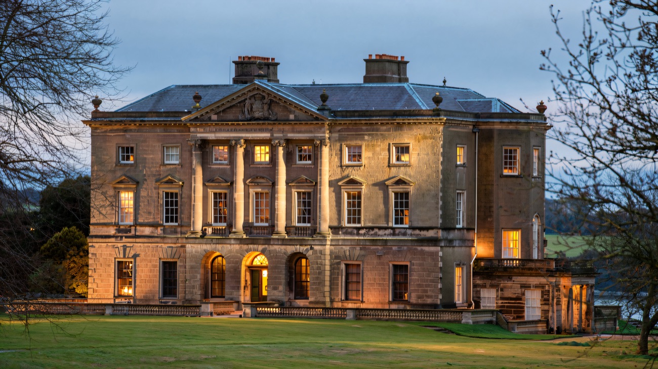 The Classical entrance front of Castle Ward mansion — symmetrical honey-stone facade above green parkland