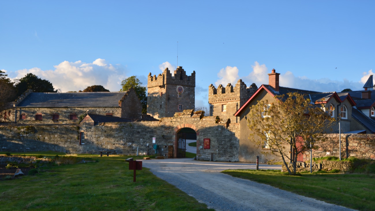 The gatehouse and battlemented tower of the Winterfell farmyard at Castle Ward under a blue sky