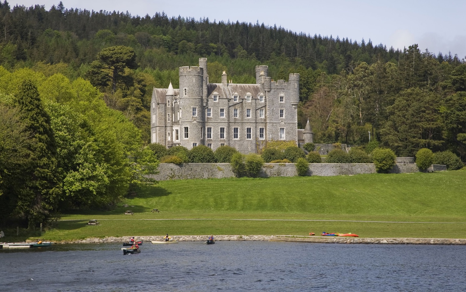Castlewellan Castle seen across the lake with a few small canoes on the water