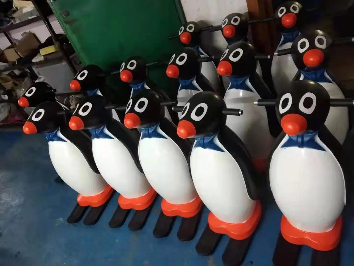 A row of penguin skate aids lined up at the edge of the ice rink