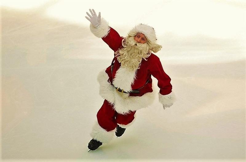 Santa in his red suit skating on the ice and waving to the crowd