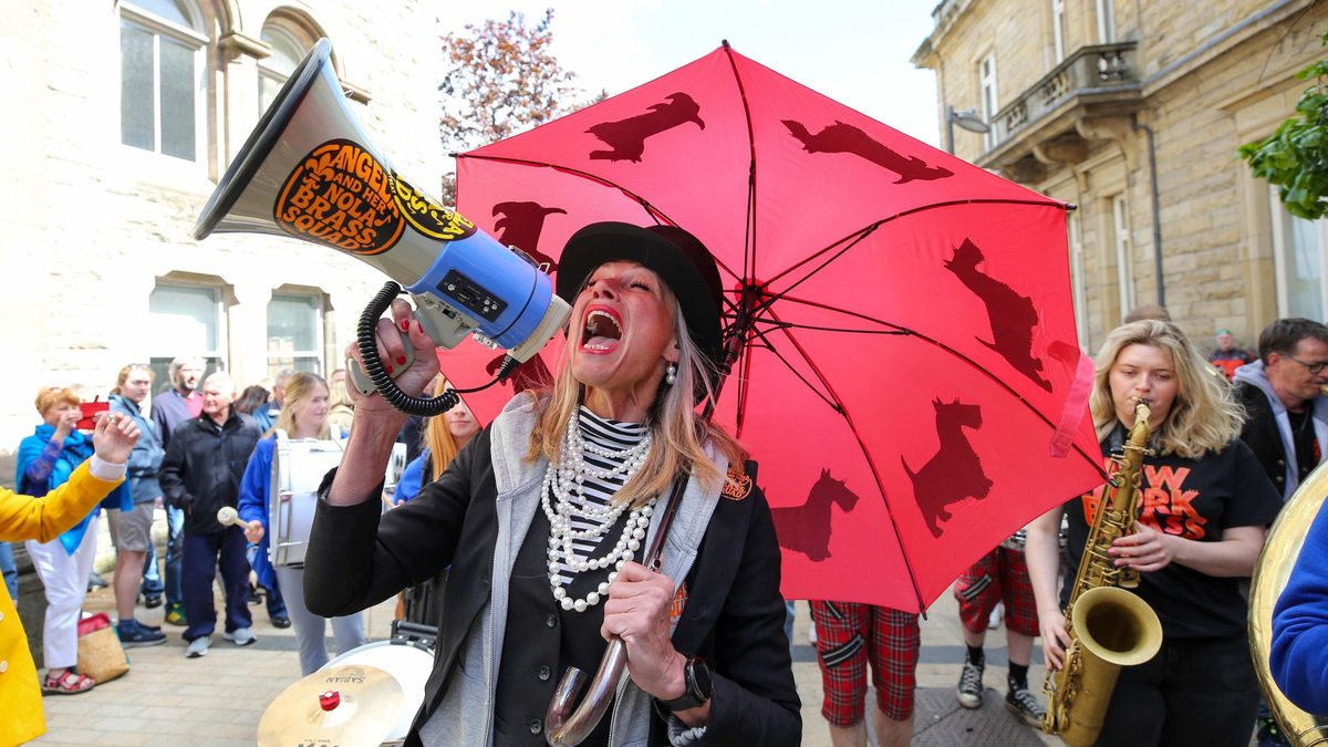 A festival singer with a red umbrella performing on the street at the City of Derry Jazz Festival