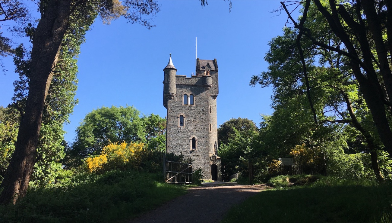 Helen's Tower rising from the trees on the Clandeboye Estate under a blue sky