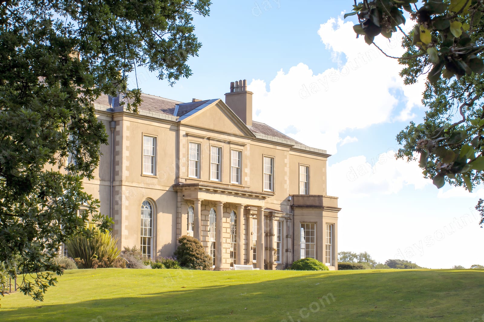 Clandeboye House, a Georgian mansion, framed by oak trees above a broad green lawn