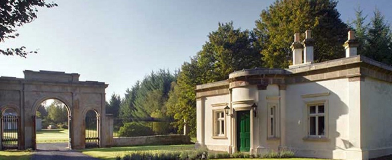The estate's triumphal-arch entrance and a rendered gate lodge cottage in morning sun