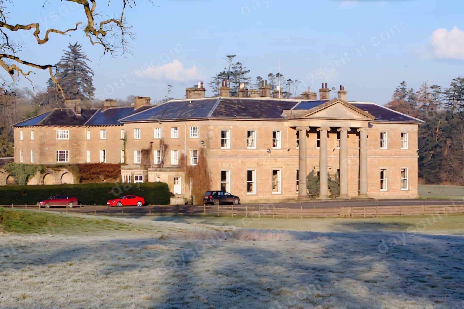 The Georgian sandstone front of Colebrooke Park with its tall columned portico, seen across frosty parkland
