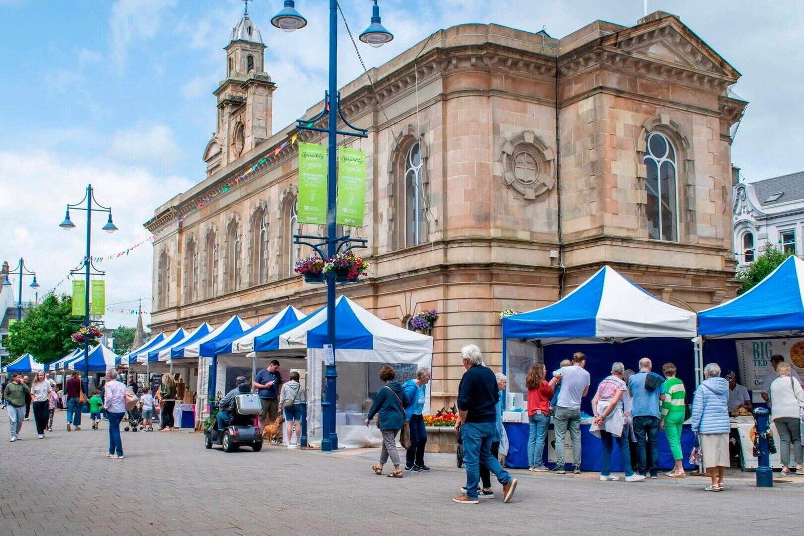 Busy market stalls and crowds filling a town square at the Comber Earlies Food Festival