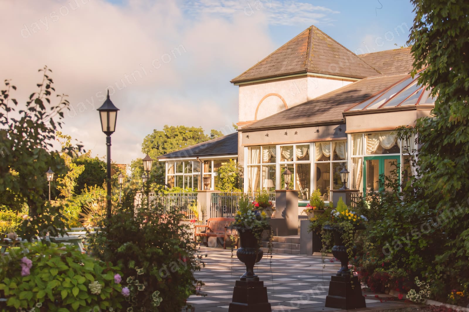 The Corick House conservatory glows gold in evening light above the estate gardens.
