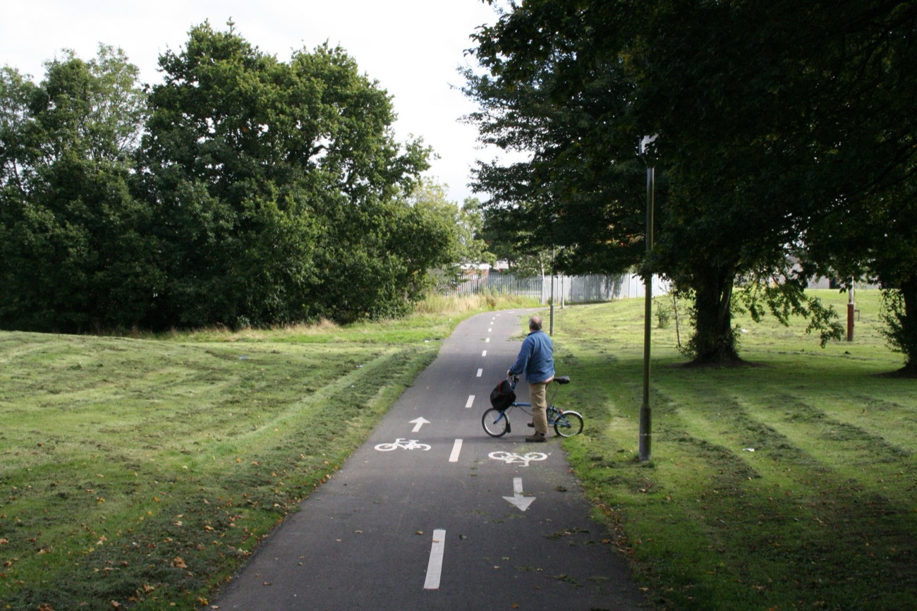 A wide surfaced cycle and walking path running between grass and trees at Craigavon Lakes