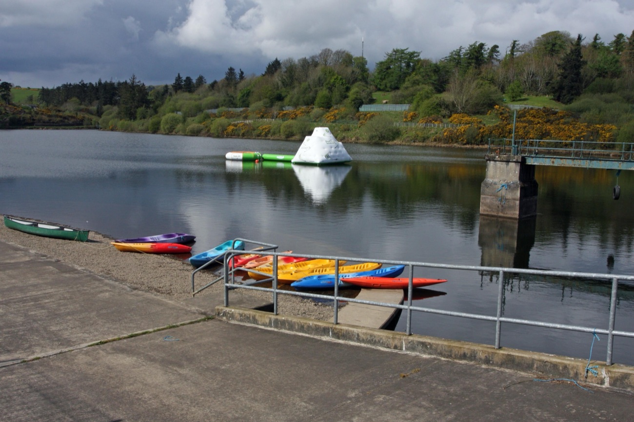 Kayaks and canoes racked on the slipway at Creggan with an inflatable aqua course out on the water